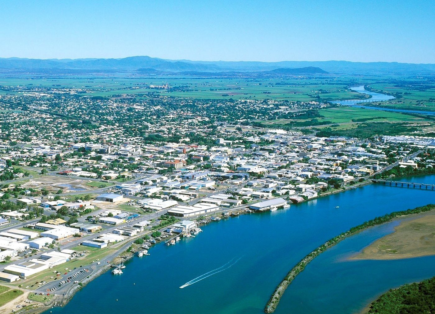 Aerial view of a coastal town with a river and mountains.