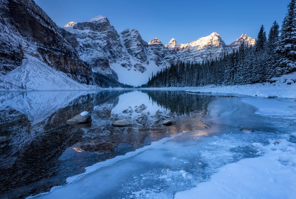 A snowy mountain next to a lake