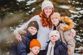 man in black jacket and blue denim jeans standing beside brown wooden box trailer during daytime