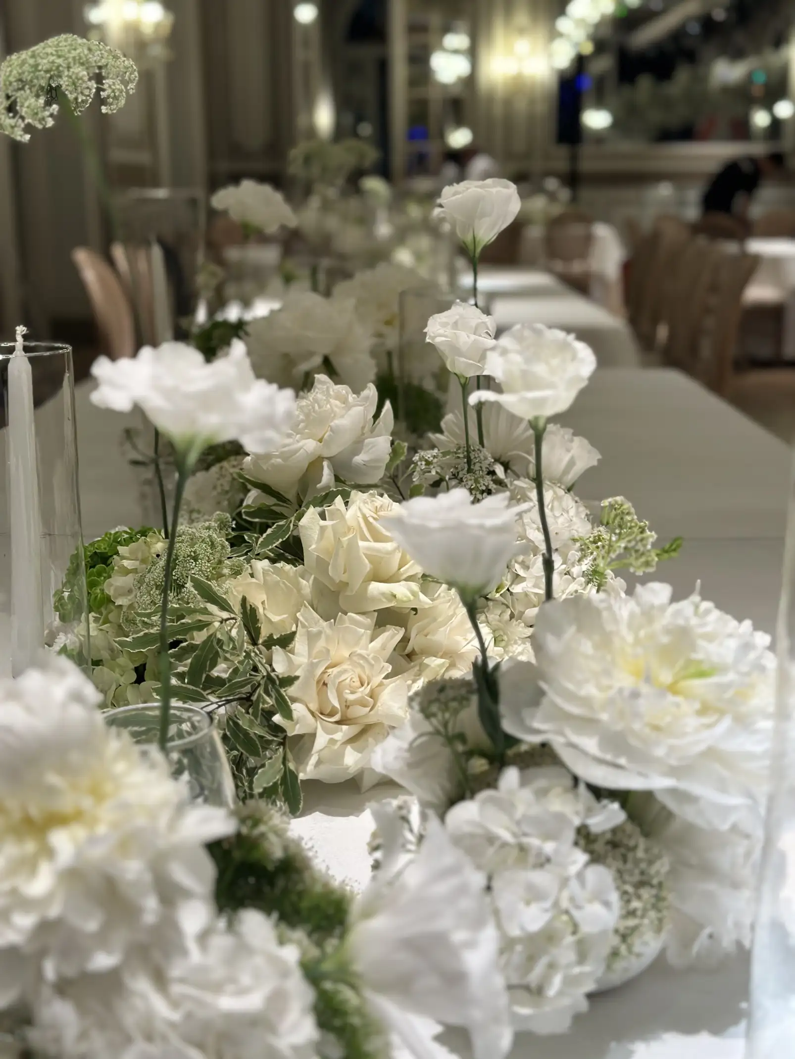 Centro de mesa blanco con flores frescas y velas para evento nocturno elegante, diseñado para transmitir armonía y luminosidad.