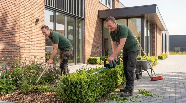 Twee hoveniers voeren onderhoud uit aan planten en heg voor een modern gebouw.