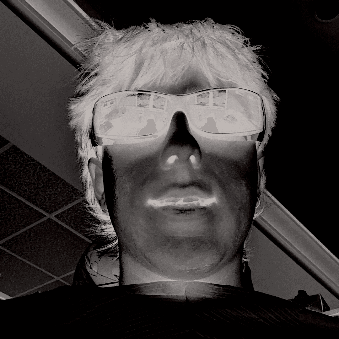 A close-up of a person wearing green-tinted glasses, with a serious expression and smooth skin.