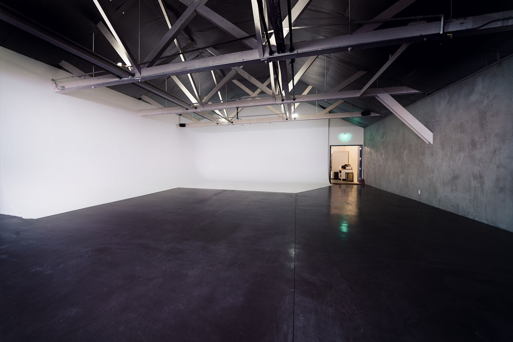 A wide image of the Cyc wall on the soundstage at Particle Studio in Seattle. The cyc wall is displayed in a 3/4 angle with white light splashing on the wall. 