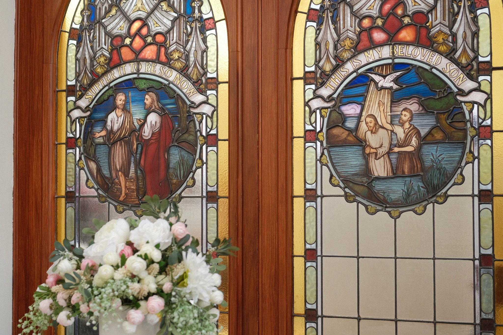 A restaurant interior featuring marble countertops, brown leather chairs, wood-paneled walls, and round pendant lights hanging above a bar set with wine glasses.