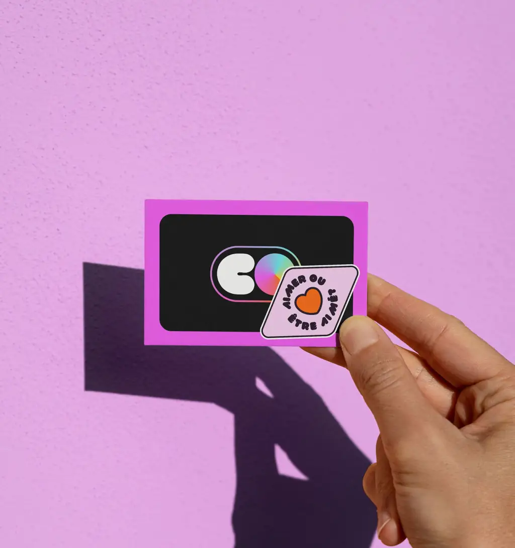 Hand holding a small purple COLORS card with a printed icon.