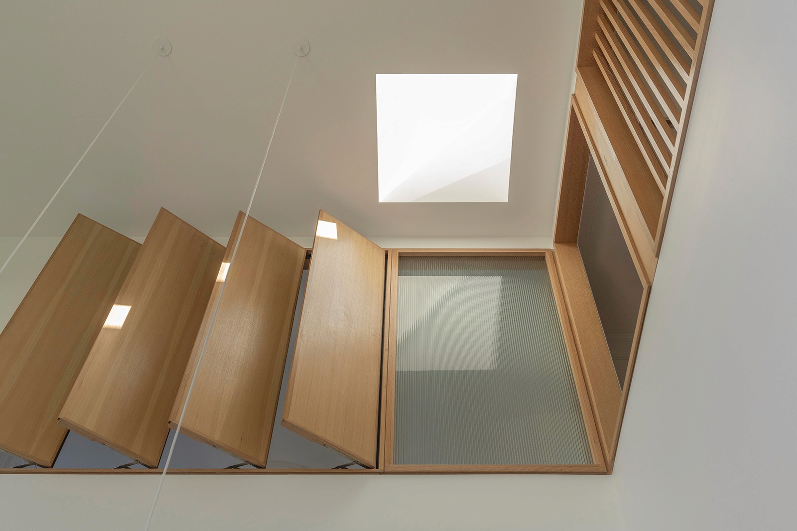 Timber screen balustrade and skylight bringing soft daylight into the upper-level void.