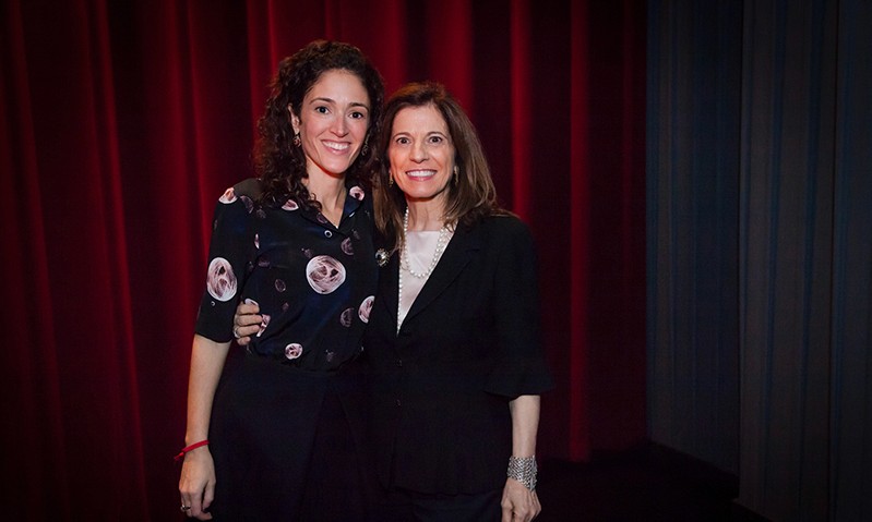 photo of two women with a red curtain behind