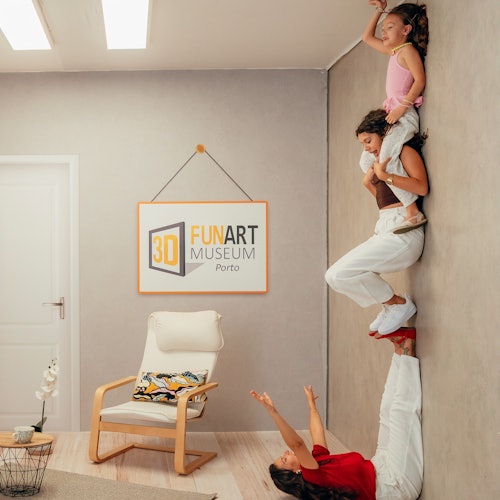 A woman lies on the floor holding another woman standing on her hands, who is carrying a child in a museum room with a "3D FUN ART MUSEUM Porto" sign.
