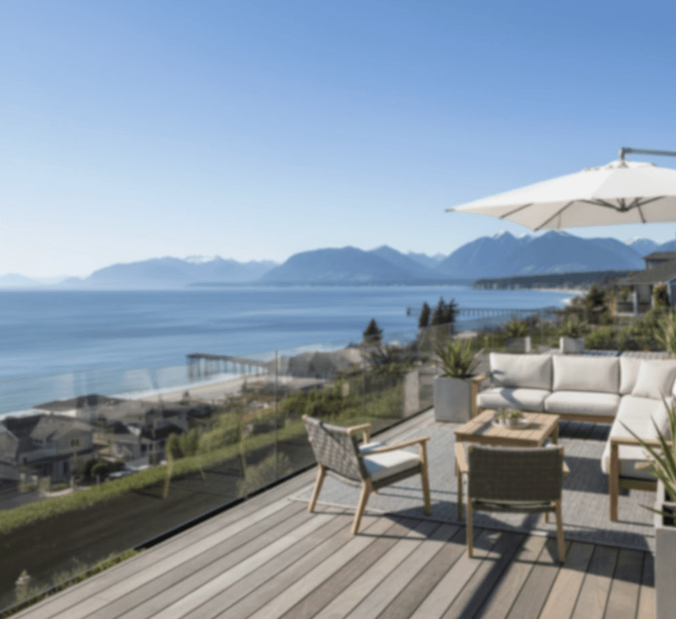 Professional photo of frameless glass deck railing with crystal clear ocean view in White Rock BC, modern residential deck with 12mm glass panels, no vertical posts, unobstructed water and mountain views in background, sunny day, high-end residential architecture