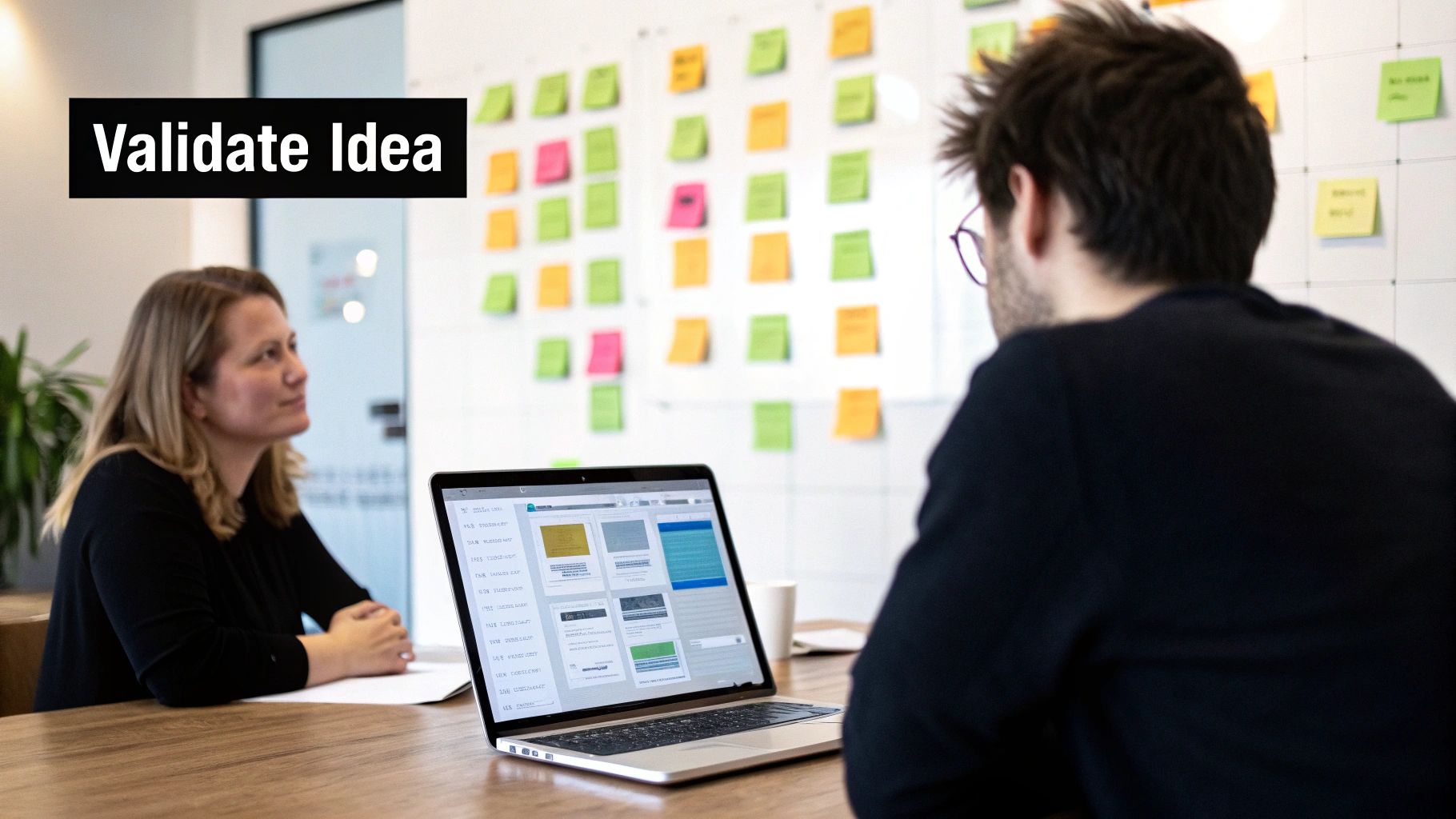 Two business professionals validating app ideas during brainstorming session with colorful sticky notes wall