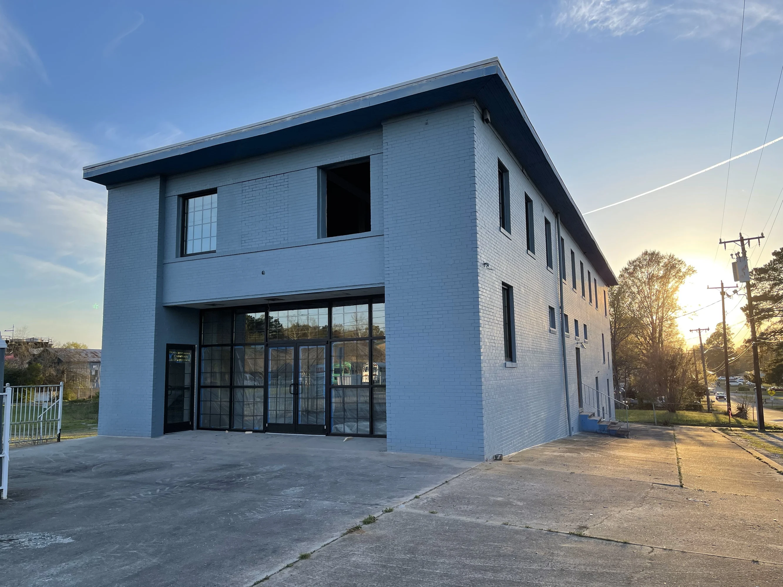 Renovated two-story brick commercial building with a glass entrance at sunset