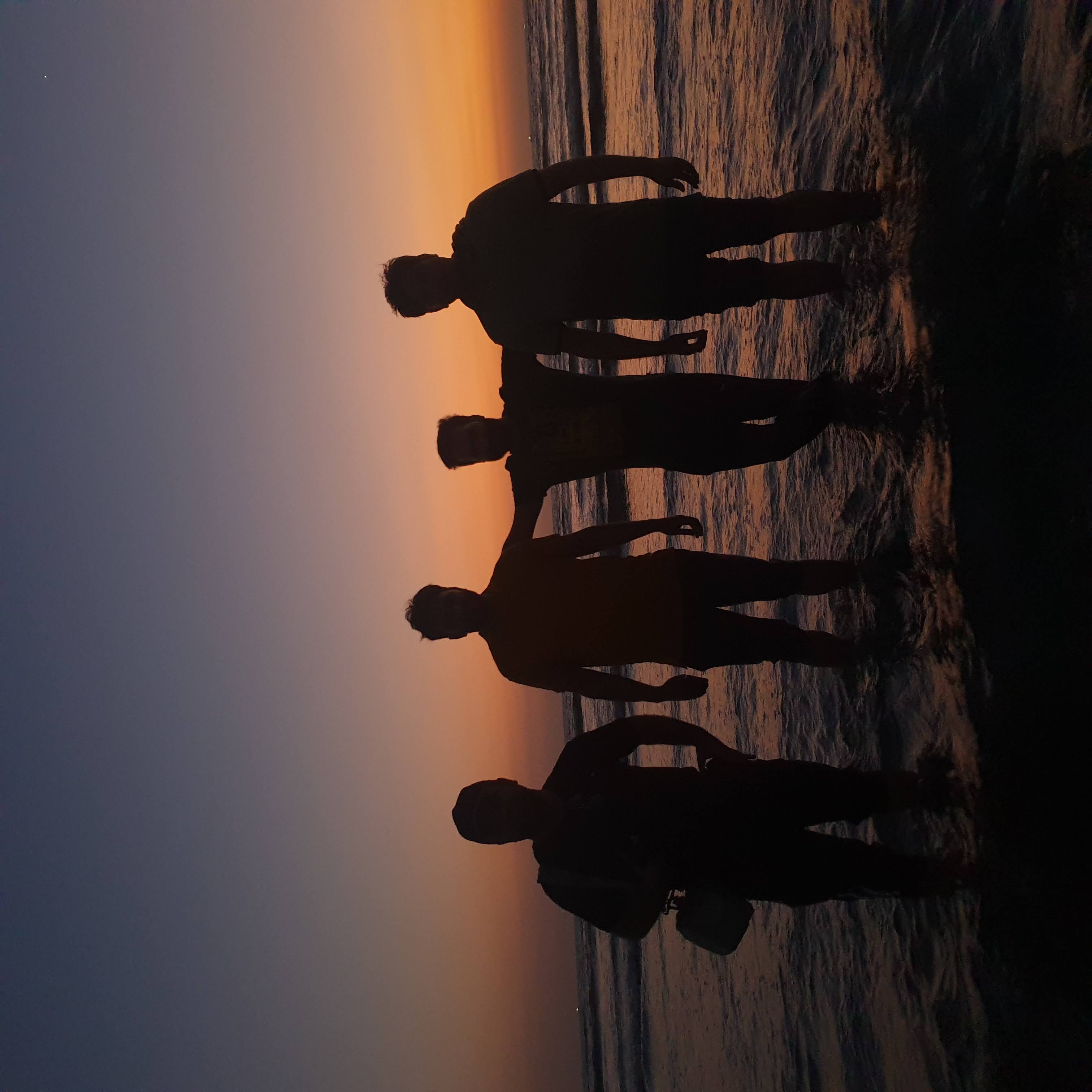 picture of silohetter of four friends standing on the beach at sunset