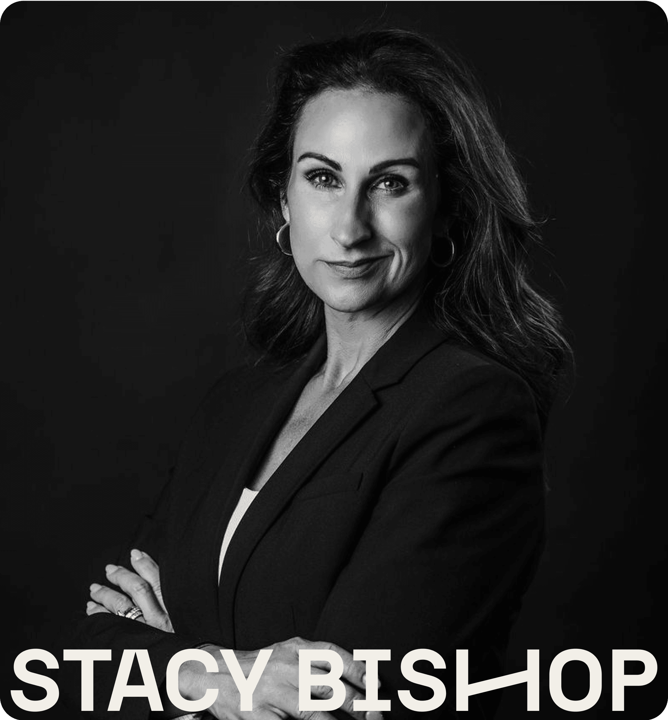 Stacy suit poses confidently against a dark background, with her arms crossed.