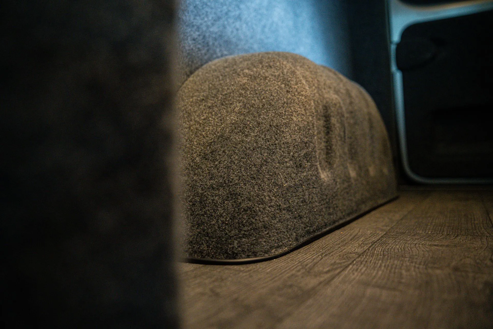 Carpet-lined wheel arch and side wall beside the Jacobean Oak floor in the Renault Trafic campervan