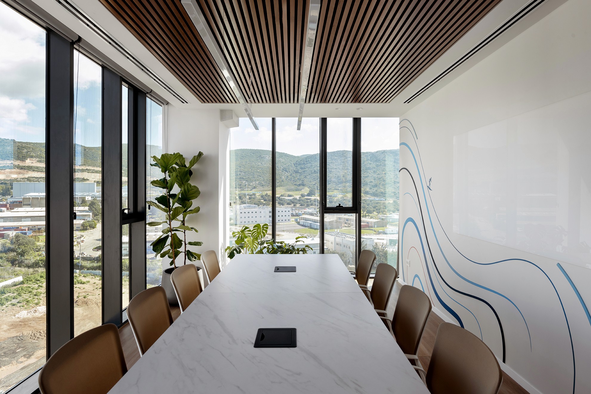 חדר ישיבות הנהלה (Boardroom) בקו ראשון לים: שימוש בתקרה אקוסטית לינארית (Linear Baffles) לשליטה בהדהוד ומיקוד במבט לנוף