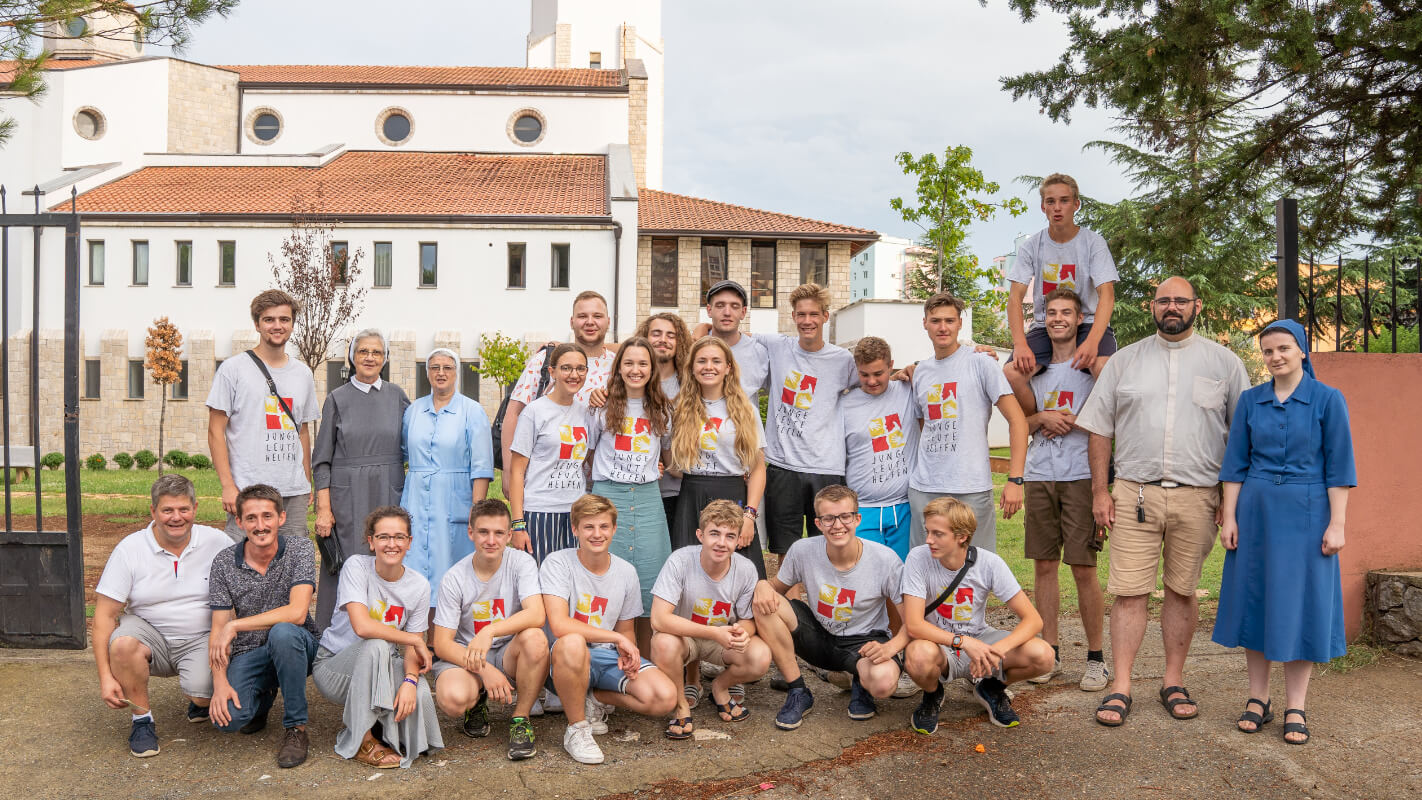 Eine Gruppe junger Leute mit Ordensschwestern steht für ein Gruppenbild zusammen Junge Leute Helfen