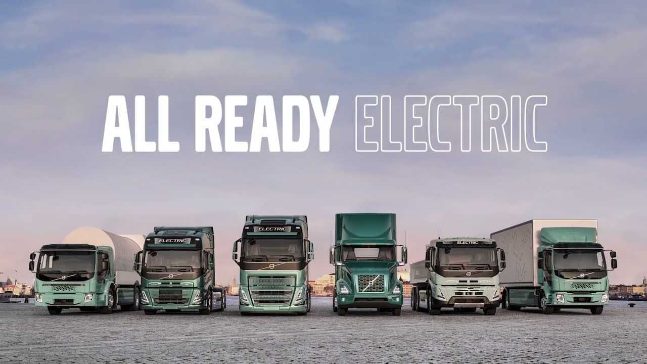 Electric truck driving on a sustainable supply chain route with renewable energy elements in the background.