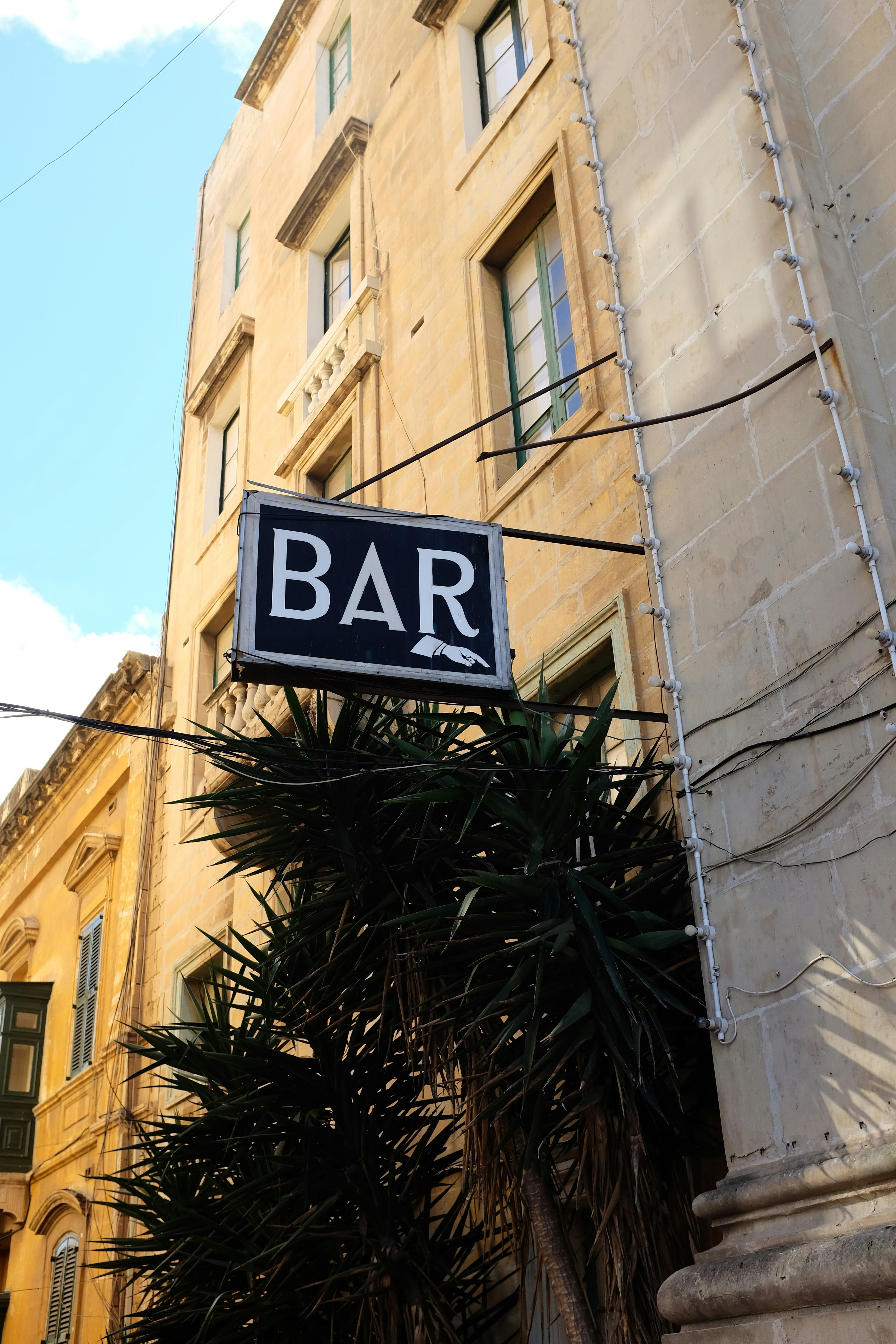 a bar sign hanging off the side of a building