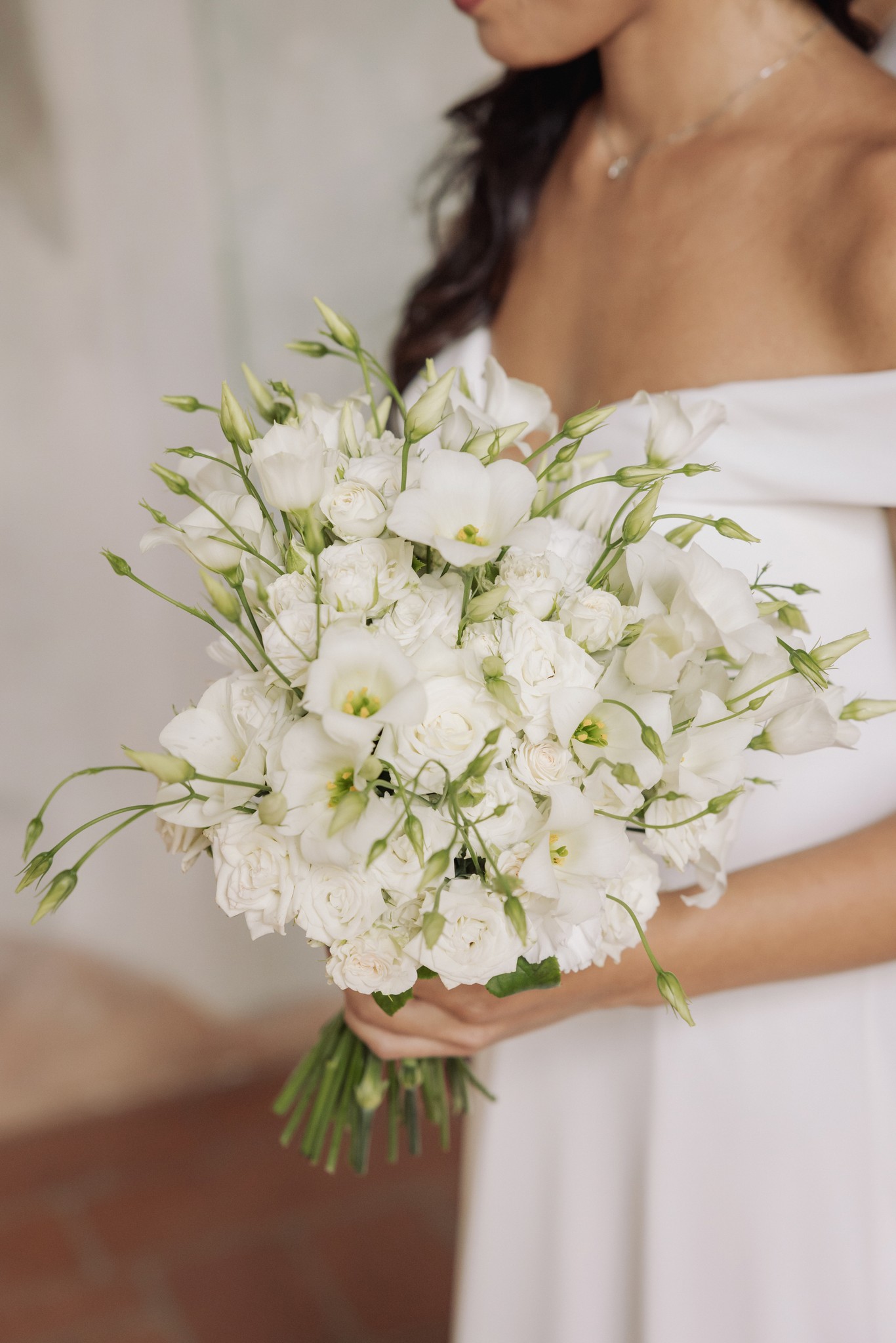 Sposa con bouquet bianco di garofani e lisianthus, dettaglio del servizio fotografico di matrimonio a Villa Negri