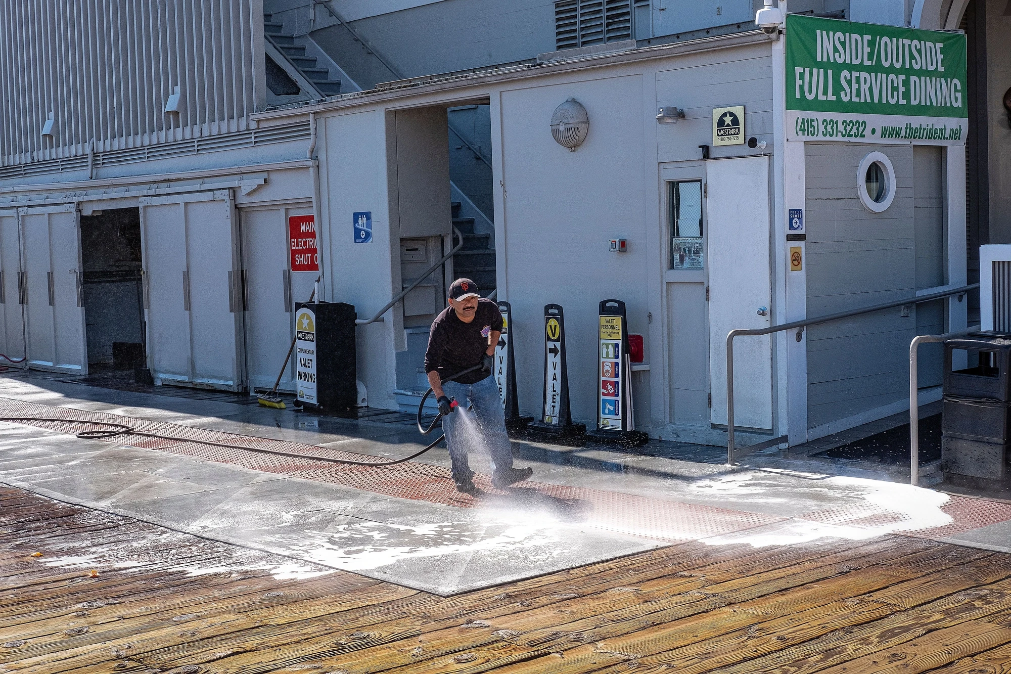 Velora technician pressure washing a driveway outside a commercial storefront