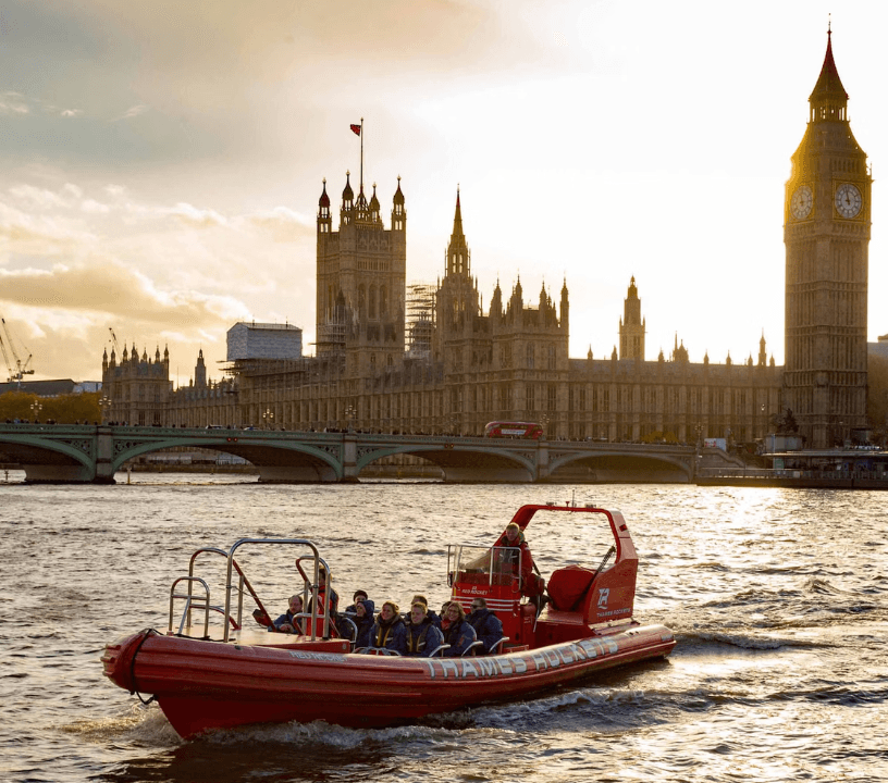 Thames Rockets Speedboat Experience: The sleek red Thames Rocket RIB speeds in front of the Tower of London with the setting sun in the back.