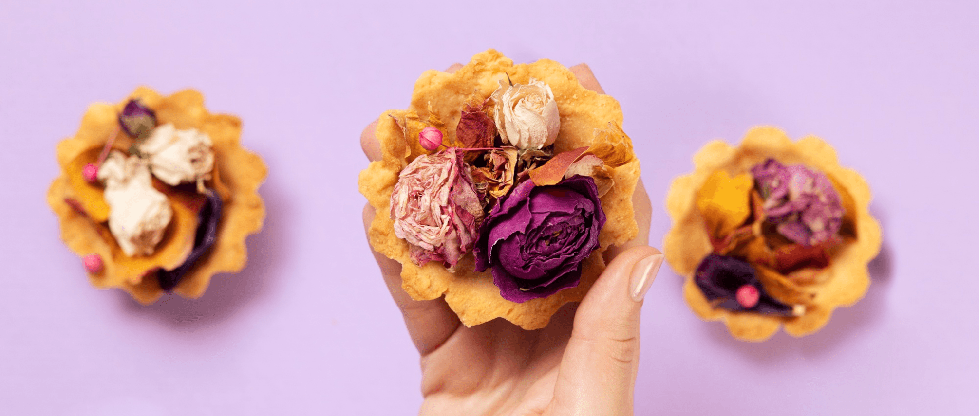  A hand holds a delicate baked tartlet shell filled with assorted dried purple