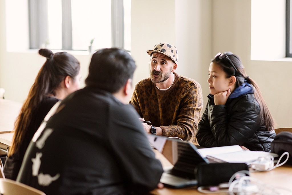 A small group in deep discussion around a table, building something together without shortcuts.