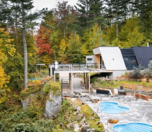 Vue sur le Spa Bolton entouré d’arbres aux couleurs d’automne, bassins d’eau chaude et installations en plein air.