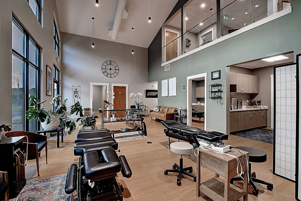 A modern, spacious salon interior with workstations, plants, and large windows letting in natural light.