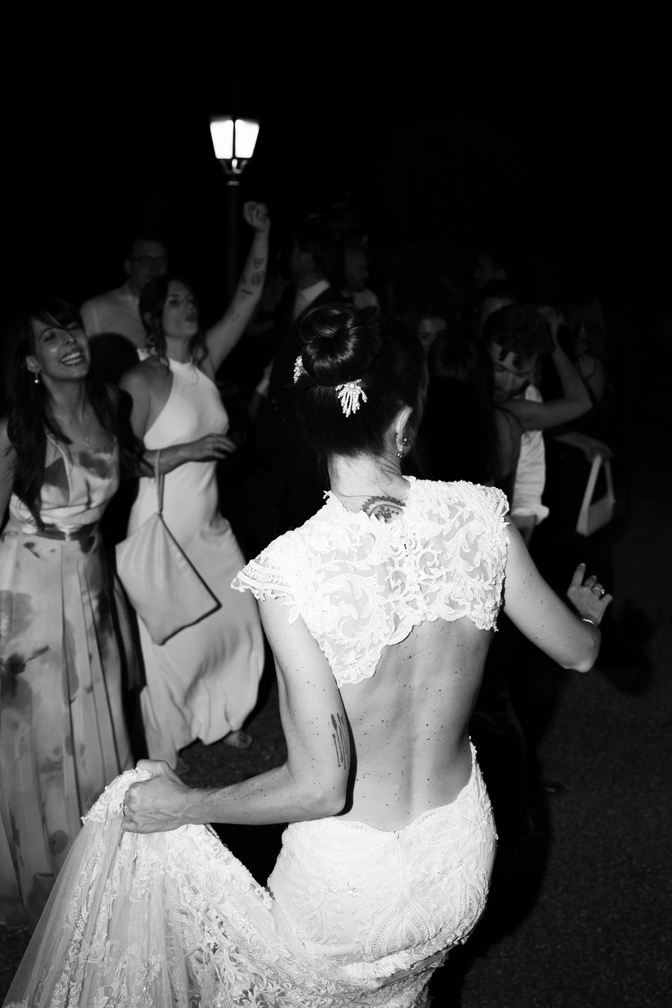 Sposa in pizzo bianco balla con gli ospiti nella notte, brindisi in sottofondo alla Rocca di Soragna