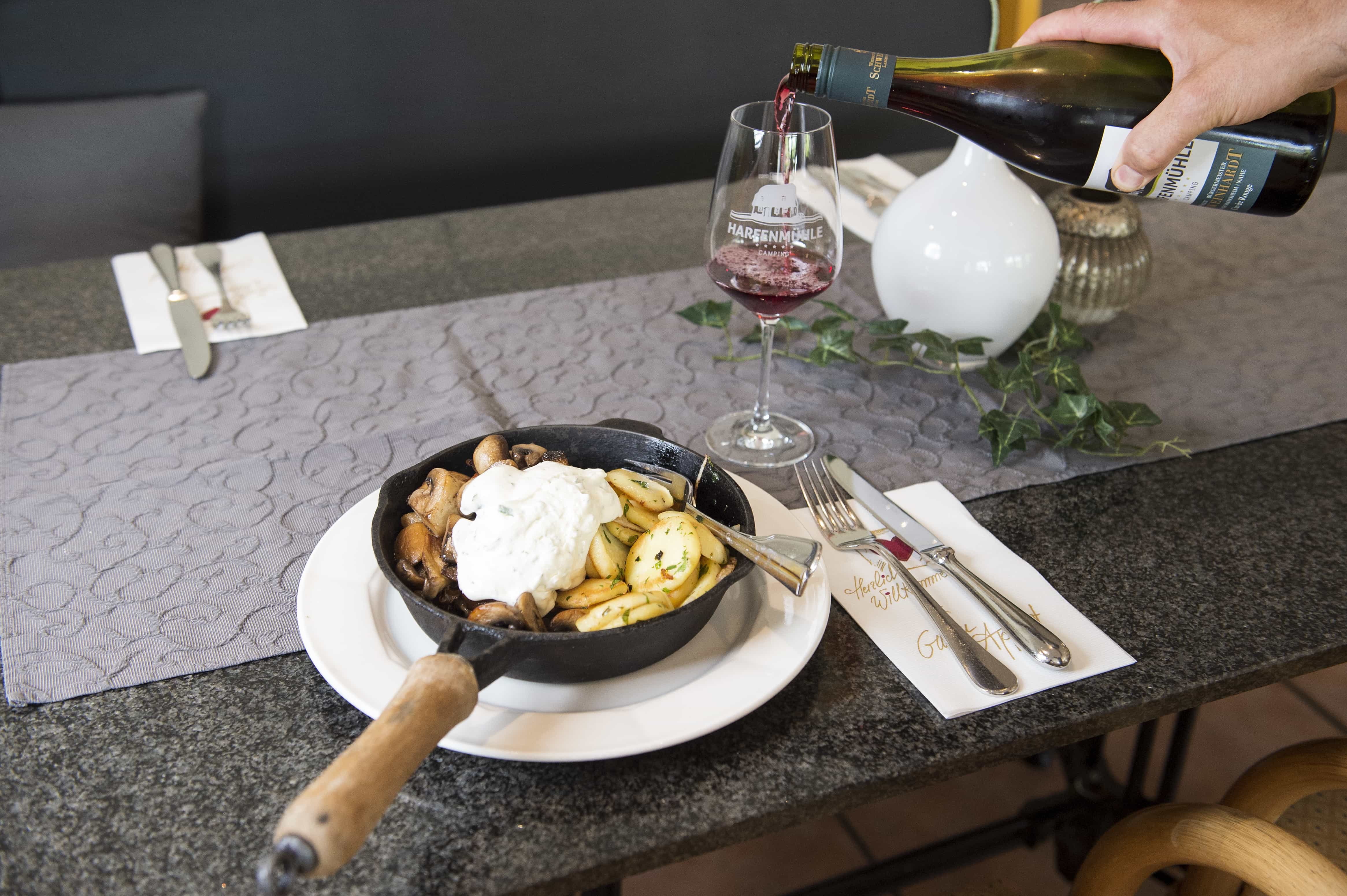 Pilzpfanne und ein Glas Rotwein wird eingeschenkt
