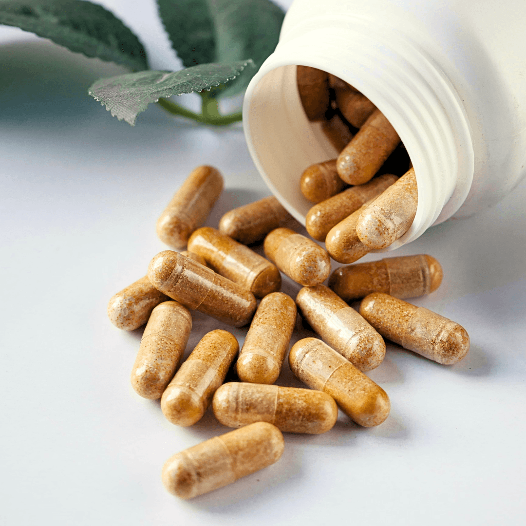 A dark glass bottle with a pump sits on a stone, surrounded by green leaves and textured background.