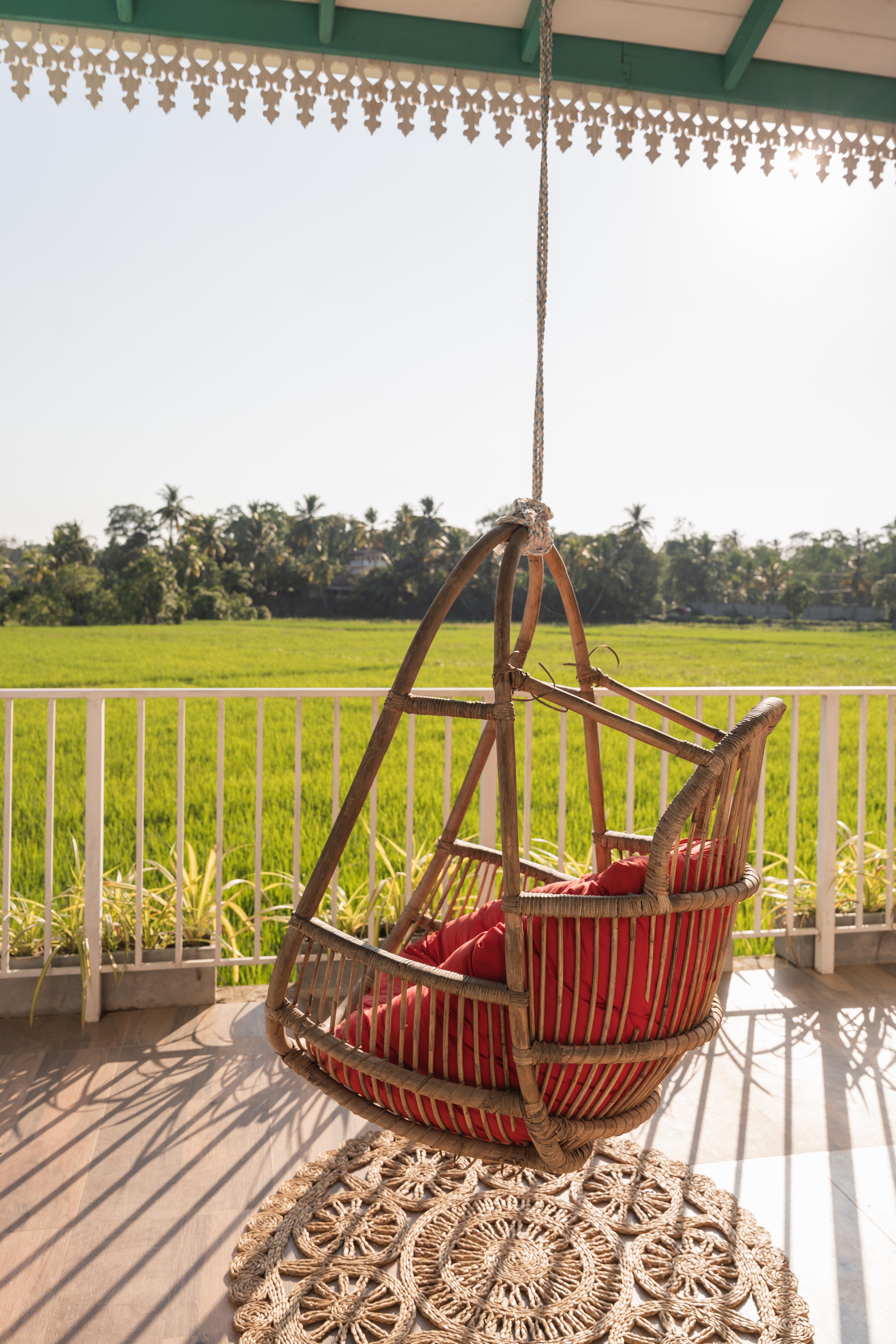 Hanging chair with pink cushion and rice fields in the back