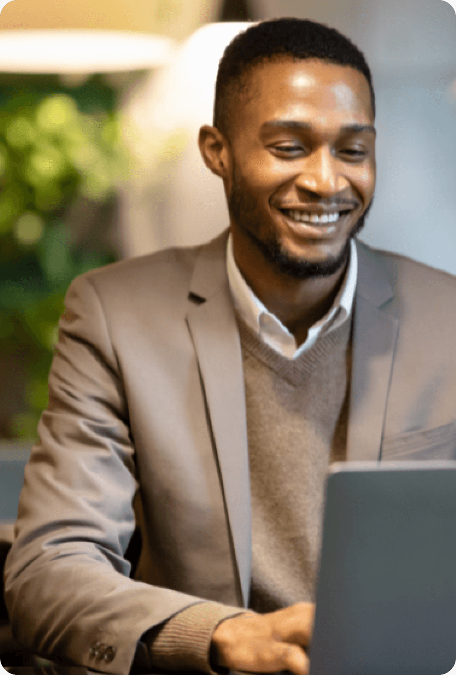 Man in a suit smiling and using his computer.