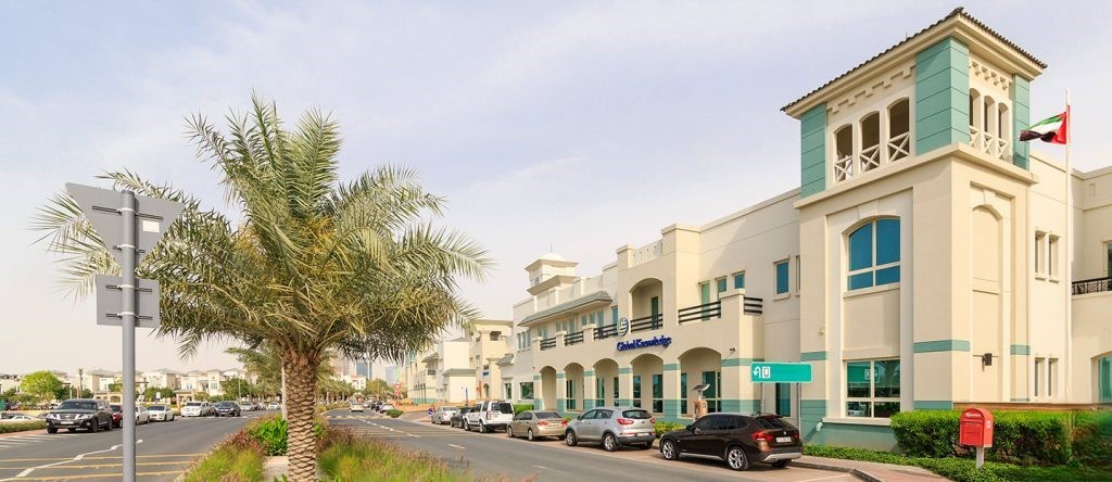 Street view of a retail and community center building on Palm Jumeirah, featuring traditional Arabic architecture and a UAE flag.