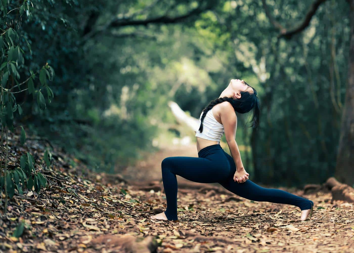 Yoga for flexibility - Woman performing a lunge stretch in the woods
