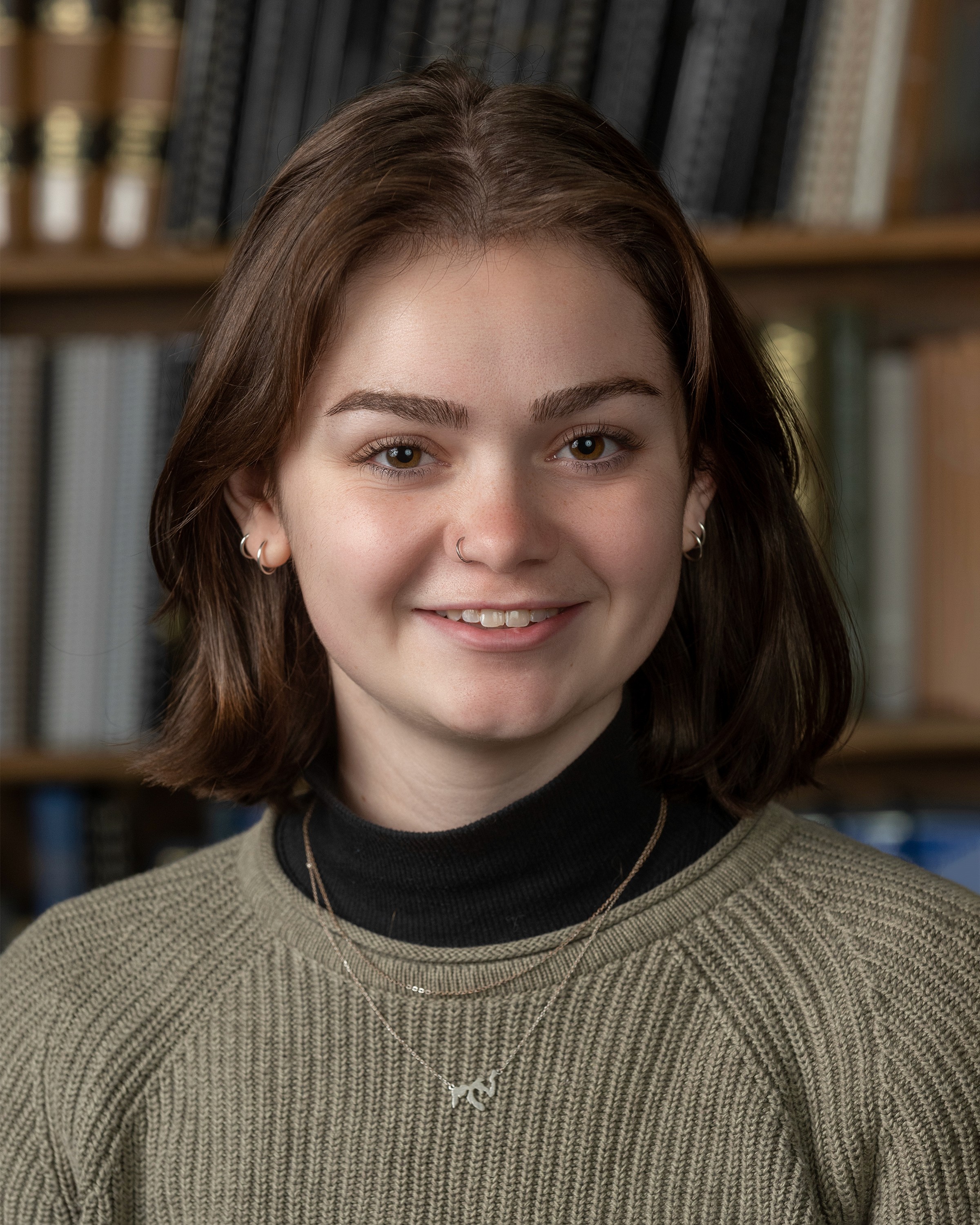 A white woman with shoulder-length brown hair, smiling in a library