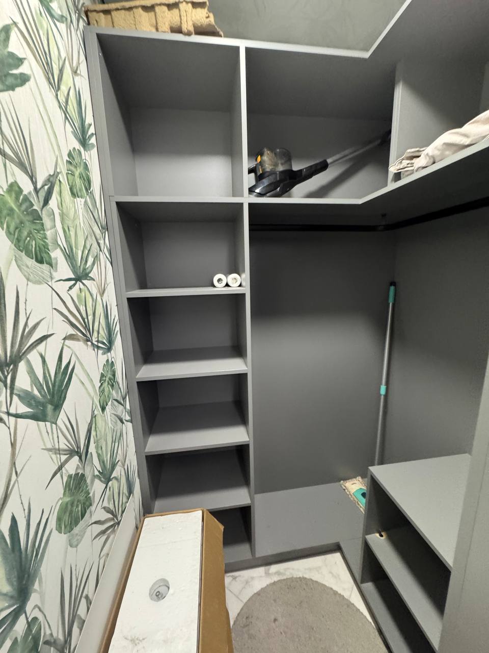 Відкрите зберігання з поличками на фоні шпалер з рослинним принтом