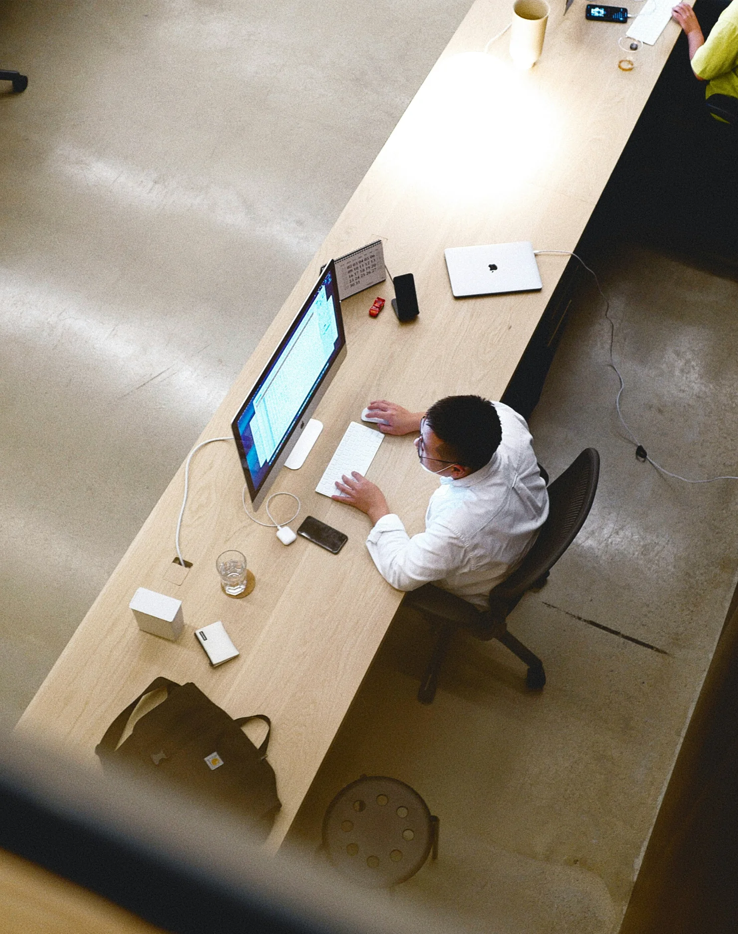Woman wearing headphones working on a laptop by window