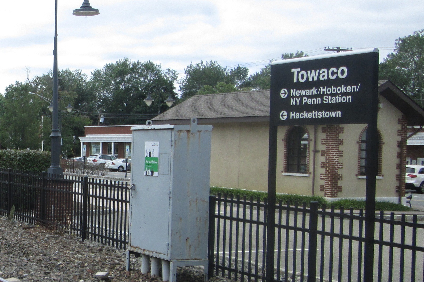 Black Towaco direction sign and station shelter beside the railway in Towaco, New Jersey.