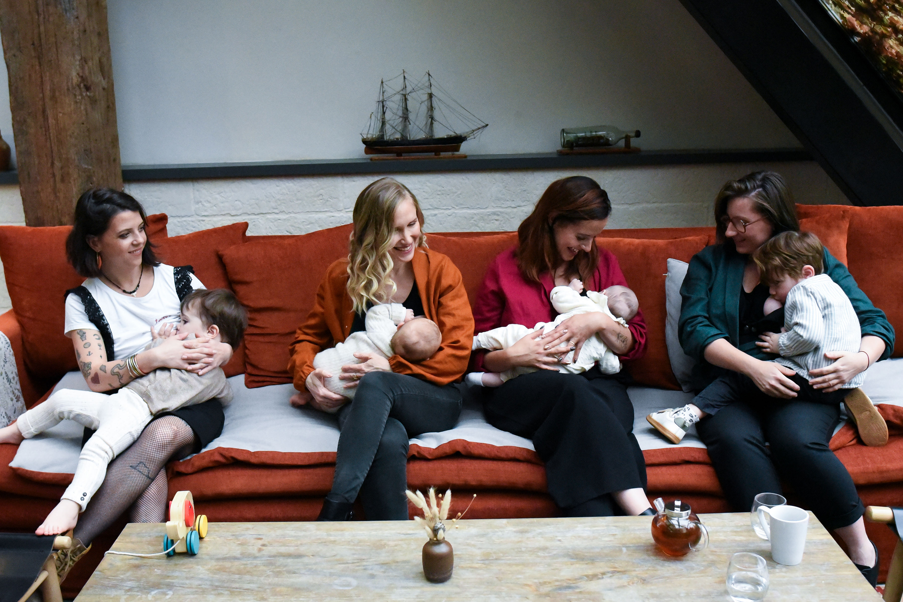 Quatre jeunes femmes élégantes portent des chemisiers d’allaitement pratiques et raffinés dans des teintes vert émeraude, orange et bordeaux. Confortables et tendance, ils permettent d’allaiter facilement grâce à des ouvertures discrètes, tout en mettant en valeur la silhouette. Parfait pour illustrer la maternité moderne et naturelle, ce visuel reflète douceur, complicité et style pour les femmes qui souhaitent allaiter avec confort et élégance.