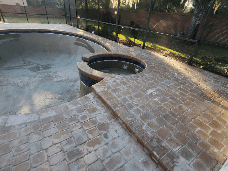 Pool deck in Oviedo, FL with failed sealer all over the pavers 