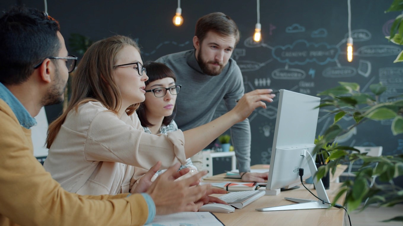 A team discussing around a screen in an office