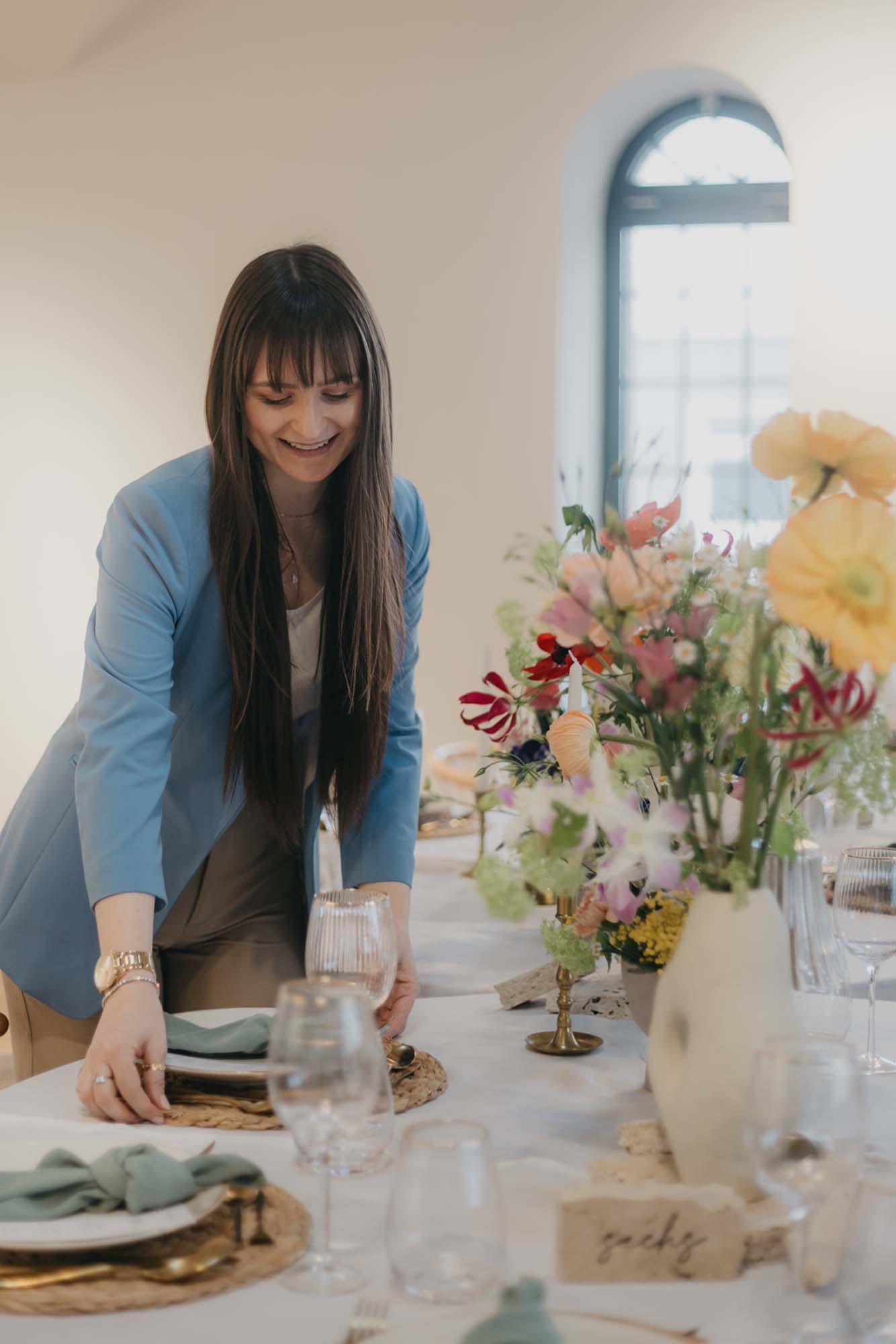 Hochzeitsplanerin Emily richtet die Tischdekoration des floralen Settings.