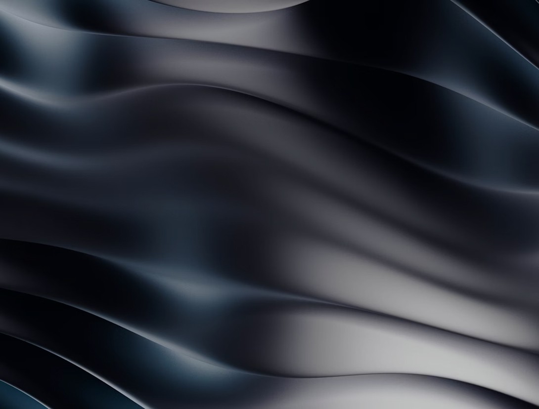 Abstract waves of dark fabric, showing smooth textures and shades of blue and black.