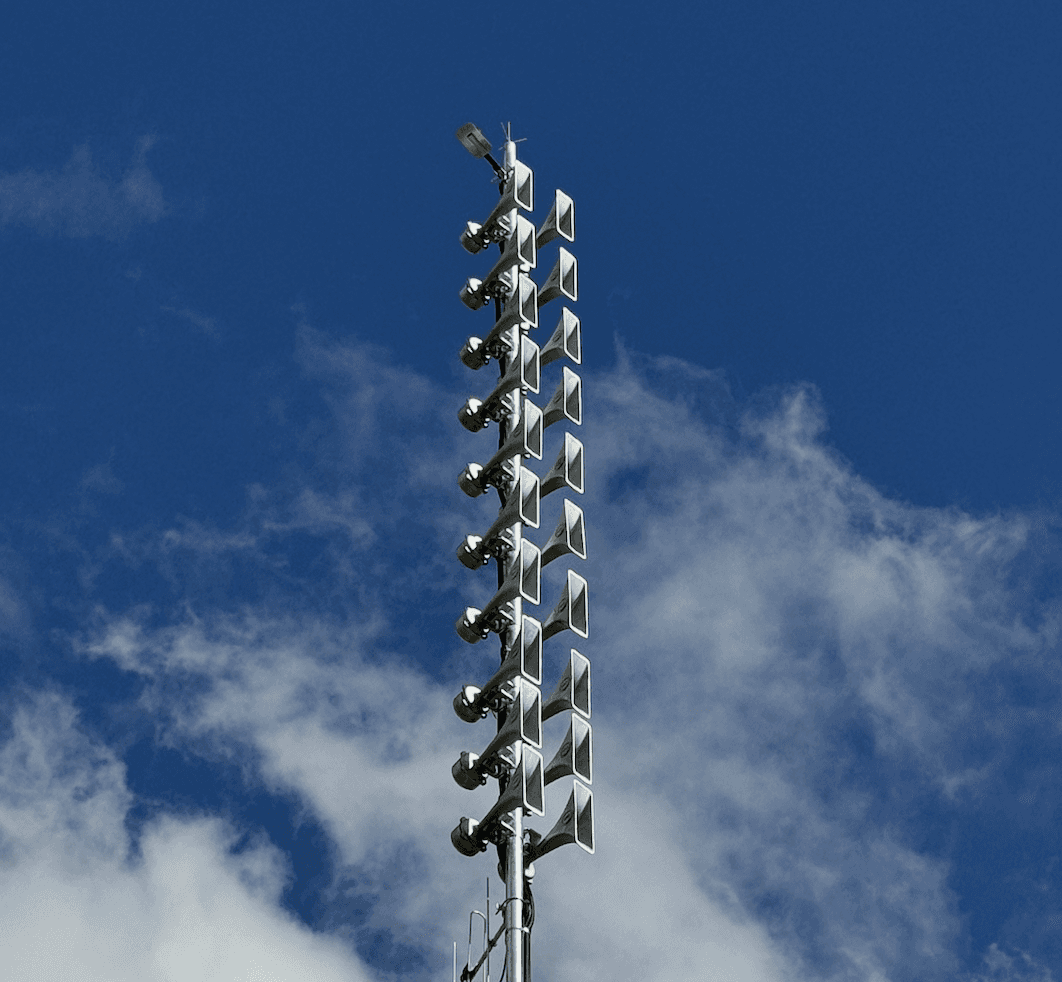 A winding road cuts through rocky terrain, surrounded by patches of green grass and illuminated by sunlight.