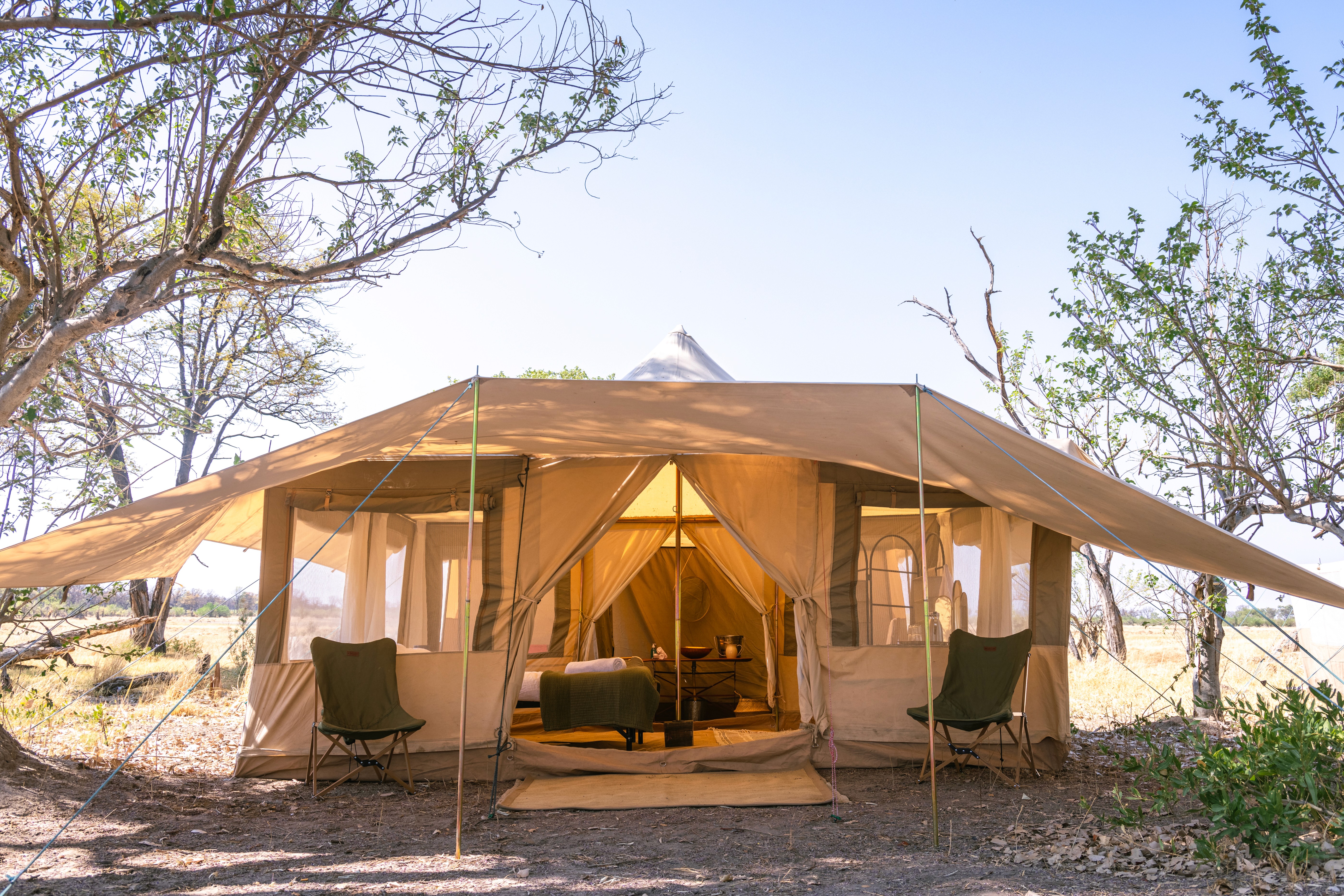 Kujwana Delta Ride, Okavango Delta, Botswana. utsidan av vackert glamping-tält uppsatt mitt i Okavangos vildmark. i tältet skymtar bekväma sängar och ensuite badrum
