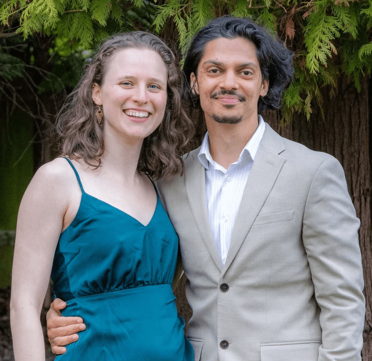 A couple dances closely, showcasing a flowing green dress, against a soft, blurred background of other guests.