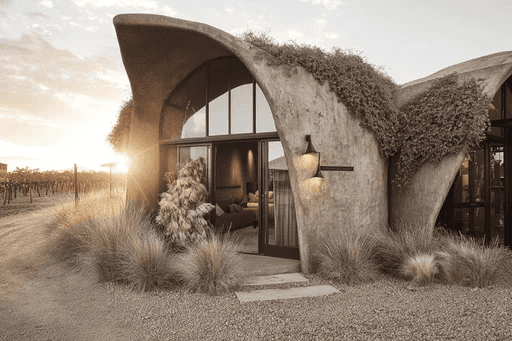 Large house with a wrap-around balcony overlooking a lit pool and deck at night.