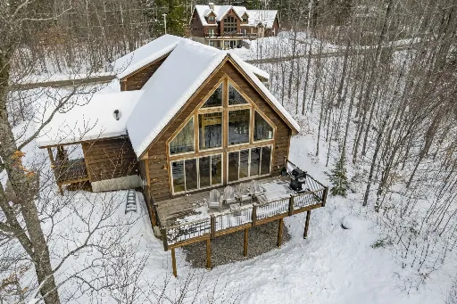 Snow-covered A-frame cabin surrounded by winter woods